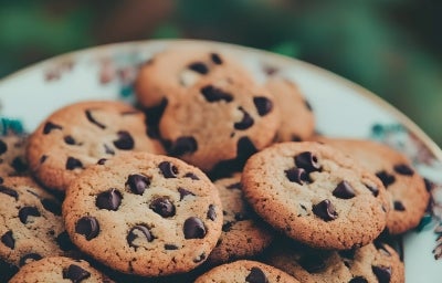 Em cima de uma mesa, prato redondo com biscoitos crocantes com gotas de chocolate. Em cima de uma mesa, prato redondo com biscoitos crocantes com gotas de chocolate.