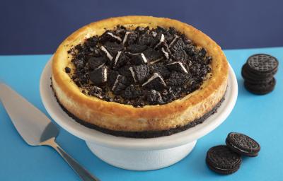 Foto da receita de Cheesecake de negresco. Observa-se a torta em uma bailarina branca com pedaços de negresco cortados no topo, em um fundo com dois tons de azuis - um mais claro e outro mais escuro. Foto da receita de Cheesecake de negresco. Observa-se a torta em uma bailarina branca com pedaços de negresco cortados no topo, em um fundo com dois tons de azuis - um mais claro e outro mais escuro.