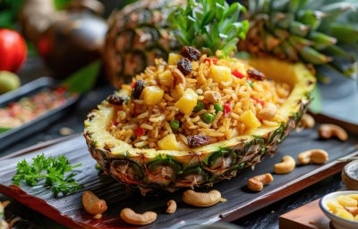 Em um abacaxi cortado ao meio, porção de arroz com abacaxi picados, ervilhas, uvas-passas e castanha-do-Pará. Em um abacaxi cortado ao meio, porção de arroz com abacaxi picados, ervilhas, uvas-passas e castanha-do-Pará.