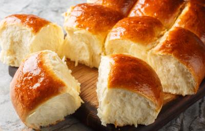 Fotografia de várias unidades pãos fofinhos de leite ninho dourados por cima. Os pães estão sobre uma tábua de madeira. Fotografia de várias unidades pãos fofinhos de leite ninho dourados por cima. Os pães estão sobre uma tábua de madeira.