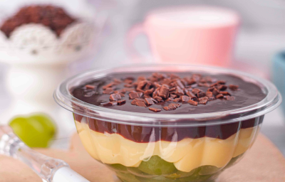 Fotografia mostra um pote transparente com camadas visíveis de uva verde, creme branco e chocolate com granulado.
