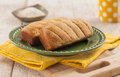 Fotografia em tons de amarelo em uma bancada de madeira clara, um pano amarelo com listras brancas, uma tábua de madeira, um prato verde redondo com dois pãezinhos em cima dele. Ao fundo, uma xícara amarela com bolinhas brancas. Fotografia em tons de amarelo em uma bancada de madeira clara, um pano amarelo com listras brancas, uma tábua de madeira, um prato verde redondo com dois pãezinhos em cima dele. Ao fundo, uma xícara amarela com bolinhas brancas.