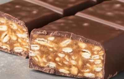 Fotografia de duas barras de chocolate com amendoim cortadas na metade sobre uma mesa de cimento queimado. Fotografia de duas barras de chocolate com amendoim cortadas na metade sobre uma mesa de cimento queimado.