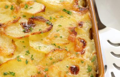 fotografia em tons de marrom e amarelo tirada de um recipiente marrom com batatas gratinadas dentro. fotografia em tons de marrom e amarelo tirada de um recipiente marrom com batatas gratinadas dentro.