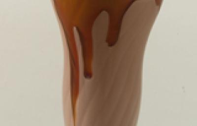 Fotografia em tons de marrom em uma bancada cinza com uma taça de vidro alta e o milkshake de chocolate dentro dela. Fotografia em tons de marrom em uma bancada cinza com uma taça de vidro alta e o milkshake de chocolate dentro dela.
