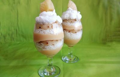 Fotografia em tons de verde com duas taças grandes de vidro ao centro. Dentro da taça existe um doce em camadas alternadas de abacaxi, coco ralado e chantilly