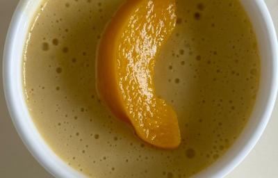 Fotografia em tons claros de três ramekins brancos sobre uma mesa branca. Dentro de cada ramekin tem uma receita de mousse de pêssego decorado com uma fatia da fruta. Fotografia em tons claros de três ramekins brancos sobre uma mesa branca. Dentro de cada ramekin tem uma receita de mousse de pêssego decorado com uma fatia da fruta.