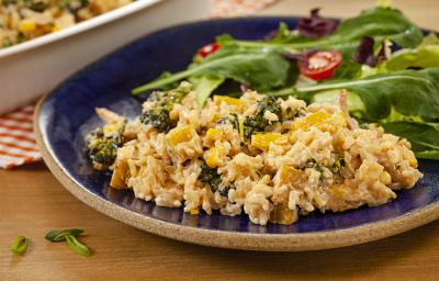 Fotografia em tons de marrom e azul de uma bancada de madeira, sobre ela um prato redondo azul com arroz e salada de folhas. Ao fundo um recipiente branco. Fotografia em tons de marrom e azul de uma bancada de madeira, sobre ela um prato redondo azul com arroz e salada de folhas. Ao fundo um recipiente branco.