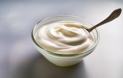 Foto aproximada de um pote de vidro com um creme branco dentro e uma colher de prata Foto aproximada de um pote de vidro com um creme branco dentro e uma colher de prata