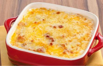 Fotografia em tons de vermelho em uma bancada de madeira com um pano amarelo e um recipiente quadrado com alças laterais vermelho e o frango gratinado dentro dele. Fotografia em tons de vermelho em uma bancada de madeira com um pano amarelo e um recipiente quadrado com alças laterais vermelho e o frango gratinado dentro dele.