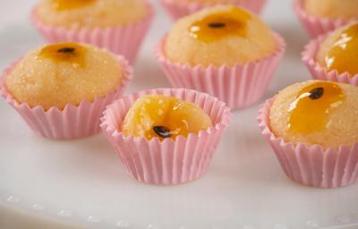 Fotografia em tons de rosa com várias forminhas de brigadeiro ao centro. Dentro de cada forminha existe brigadeiros feitos de maracujá finalizados com geleia de maracujá no topo. Fotografia em tons de rosa com várias forminhas de brigadeiro ao centro. Dentro de cada forminha existe brigadeiros feitos de maracujá finalizados com geleia de maracujá no topo.