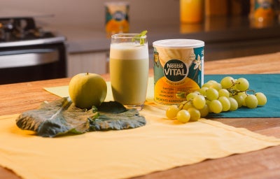 imagem mostra um copo de suco verde cremoso, servido gelado e decorado com folhas de hortelã