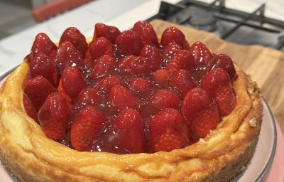 Fotografia em tons claros de uma receita de cheesecake com morango em um prato raso de tom pastel sobre uma tábua de madeira. Fotografia em tons claros de uma receita de cheesecake com morango em um prato raso de tom pastel sobre uma tábua de madeira.