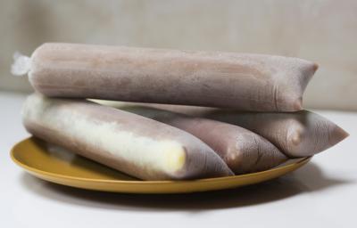Fotografia em tons claros de quatro geladinhos de chocolate sobre um prato raso médio apoiado em uma mesa branca.