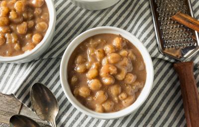 Foto da receita de Canjica de Doce de Leite. Observa-se uma foto superior de uma tigela branca com a preparação dentro e, ao lado, um ralador com a canela em pau.