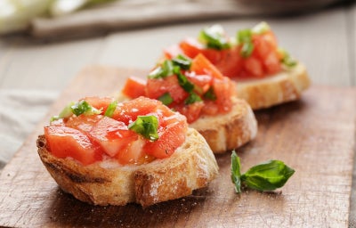 Bruschettas com pão baguete tostado, tomate picado, manjericão e azeite, servidas como aperitivo
