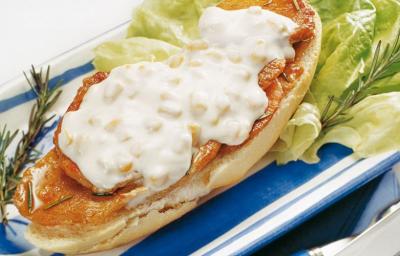 fotografia em tons de branco e azul tirada de uma bandeja azul com sanduiche com pedaços de lombo e creme branco por cima