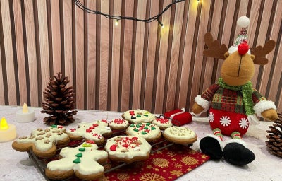 Fotografia em tons de vermelho com uma bandeja de biscoitos natalinos decorados ao centro.