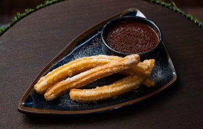 Churros espanhóis crocantes polvilhados com açúcar servidos com calda de chocolate e baunilha