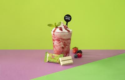 Foto em tons de cor de rosa e verde da receita de smoothie iogurte servida em um copo alto sobre uma mesa cor de rosa com um kit kat hortelã à frente Foto em tons de cor de rosa e verde da receita de smoothie iogurte servida em um copo alto sobre uma mesa cor de rosa com um kit kat hortelã à frente