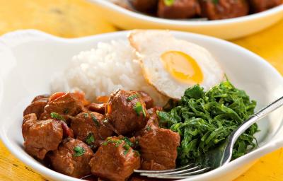 fotografia vista de frente, contém dois recipiente branco e redondo e ambos contém: arroz, couve, pedaços de carne e ovo com um garfo para servir fotografia vista de frente, contém dois recipiente branco e redondo e ambos contém: arroz, couve, pedaços de carne e ovo com um garfo para servir