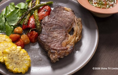 Bife de chorizo grelhado com legumes confitados, espiga de milho em rodelas e vinagrete ao lado