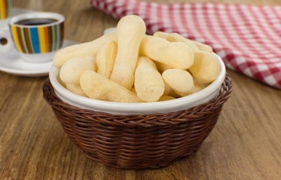 Em cima de uma mesa, tigela com biscoitos de polvilho crocantes e dourados.