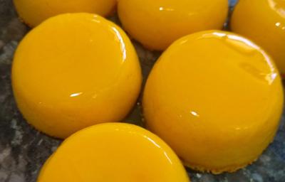 Foto da receita de Quindim. Observa-se quindins bem brilhosos e amarelinhos em uma superfície. Foto da receita de Quindim. Observa-se quindins bem brilhosos e amarelinhos em uma superfície.