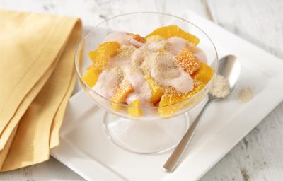 Fotografia em tons de branco e amarelo de uma bancada branca com um prato retangular branco, sobre ele uma taça com a salada de frutas e uma colher. Ao lado um paninho amarelo. Fotografia em tons de branco e amarelo de uma bancada branca com um prato retangular branco, sobre ele uma taça com a salada de frutas e uma colher. Ao lado um paninho amarelo.