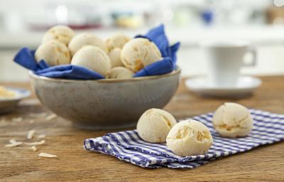 Foto de uma mesa com um pano e 3 pães de queijo redondos em cima. No fundo da foto há uma tigela com mais pães dentro Foto de uma mesa com um pano e 3 pães de queijo redondos em cima. No fundo da foto há uma tigela com mais pães dentro