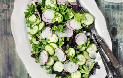 Fotografia vista de cima de um recipiente de vidro raso branco, com uma salada de acelga com cebolinha-verde com tempero, vinagre, azeite e limão.