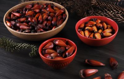 Fotografia em tons escuros com 3 potes ao centro. Em cima de cada pote existe uma receita de pinhão cozido que foi feito na airfryer.