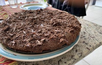 Fotografia de uma torta de chocolate com raspas de chocolate sobre um apoio branco com borda azul. Fotografia de uma torta de chocolate com raspas de chocolate sobre um apoio branco com borda azul.