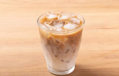 Fotografia em tons de marrom claro com um copo de vidro ao centro. Dentro do copo existe uma receita de café com leite gelado com vários cubos de gelo. Fotografia em tons de marrom claro com um copo de vidro ao centro. Dentro do copo existe uma receita de café com leite gelado com vários cubos de gelo.