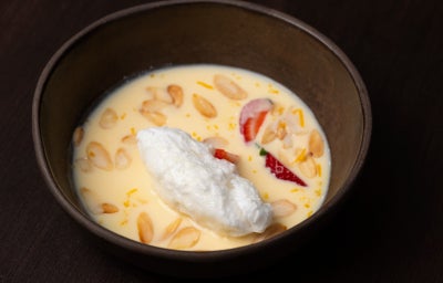 Ovos nevados sobre creme inglês com amêndoas torradas e morango fatiado