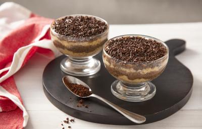 Foto da receita de Bolo de Brigadeiro de Café no Potinho. Observa-se dois potinhos transparentes intercalando uma camada de bolo branco e uma camada de brigadeiro de café. No topo, granulados para decorar. Foto da receita de Bolo de Brigadeiro de Café no Potinho. Observa-se dois potinhos transparentes intercalando uma camada de bolo branco e uma camada de brigadeiro de café. No topo, granulados para decorar.