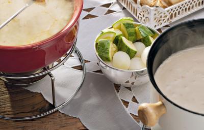 recipientes nas cores vermelho e branco ambos comporta o fondue de queijo, outros recipientes estão com os acompanhamentos para o fondue como pão, presunto entre outros. recipientes nas cores vermelho e branco ambos comporta o fondue de queijo, outros recipientes estão com os acompanhamentos para o fondue como pão, presunto entre outros.