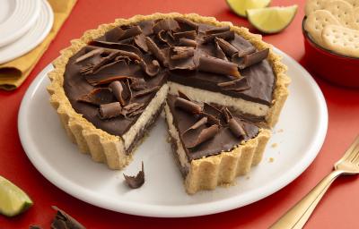 Foto da receita de Torta de Limão com Chocolate. Observa-se uma torta com cobertura de ganache e raspas de chocolate com um pedaço fatiado. Foto da receita de Torta de Limão com Chocolate. Observa-se uma torta com cobertura de ganache e raspas de chocolate com um pedaço fatiado.