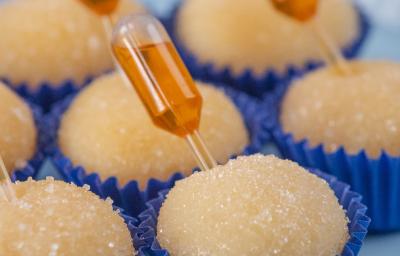 Fotografia de sete forminhas azuis juntas com brigadeiro de pudim, em cada unidade tem uma mini pipeta espetada com calda de caramelo. Os brigadeiros estão apoiados em um apoio decorativo azul claro. Fotografia de sete forminhas azuis juntas com brigadeiro de pudim, em cada unidade tem uma mini pipeta espetada com calda de caramelo. Os brigadeiros estão apoiados em um apoio decorativo azul claro.