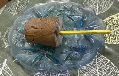 Foto da receita de Picolé de Chococream. Observa-se um picolé de chocolate sobre um prato transparente de vidro.