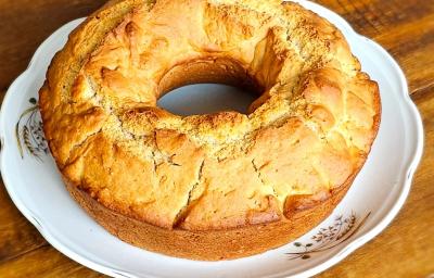 Foto aproximada da receita de pão americano, redondo, com um furo no meio, servido sobre um prato branco em uma mesa de madeira