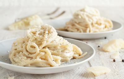Foto da receita de Macarrão Cacio e Pepe. Observa-se dois pratos com o macarrão espaguete, polvilhado de queijo e pimenta-do-reino preta. Foto da receita de Macarrão Cacio e Pepe. Observa-se dois pratos com o macarrão espaguete, polvilhado de queijo e pimenta-do-reino preta.