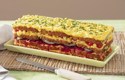 Foto da receita de Torta Fria Vegetariana. Observa-se a torta em um recipiente retangular com camadas de legumes e maionese. No topo, maionese com cheiro-verde bem picadinho. Foto da receita de Torta Fria Vegetariana. Observa-se a torta em um recipiente retangular com camadas de legumes e maionese. No topo, maionese com cheiro-verde bem picadinho.