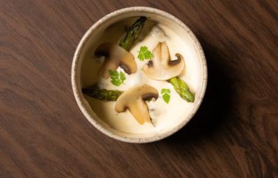 Foto da Receita de Escargot com Creme de Batatas e Natas. Observa-se uma tigela vista de cima com o creme de batatas e decorada com cogumelos, cabeças de aspargos e ramos de salsinha (cerefólio) Foto da Receita de Escargot com Creme de Batatas e Natas. Observa-se uma tigela vista de cima com o creme de batatas e decorada com cogumelos, cabeças de aspargos e ramos de salsinha (cerefólio)