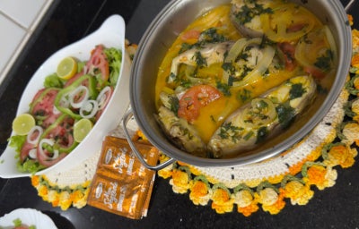 Moqueca de tilápia com tomates, cebolas e pimentões em uma travessa