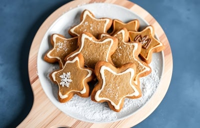 Em cima de uma mesa, prato com biscoitos em formato de estrelas, decorado com glacê branco. Em cima de uma mesa, prato com biscoitos em formato de estrelas, decorado com glacê branco.