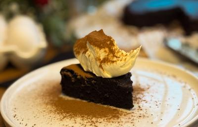Fotografia de uma fatia do fondant em um prato grande branco raso branco. Por cima tem um creme e chocolate em pó polvilhado. Fotografia de uma fatia do fondant em um prato grande branco raso branco. Por cima tem um creme e chocolate em pó polvilhado.