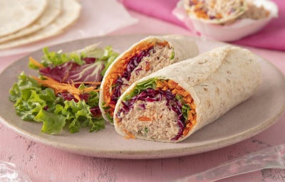 Imagem mostra um pão estilo tortilha, recheado de um creme com pedaços de legume ralados e folhas de alface