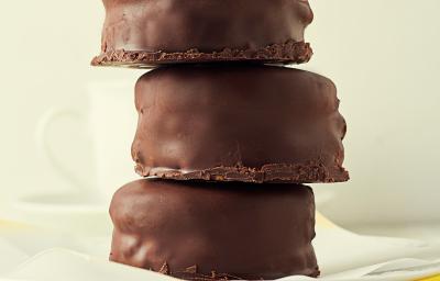 Fotografia de três pães de mel cobertos com chocolate, estão empilhados, um por cima do outro.arfo. Fotografia de três pães de mel cobertos com chocolate, estão empilhados, um por cima do outro.arfo.