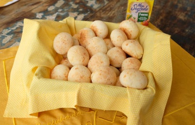 Pão de queijo em uma travessa com guardanapo amarelo